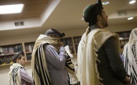 תפילת שחרית במקום הפיגוע בבית הכנסת בירושלים (צילום: רויטרס)