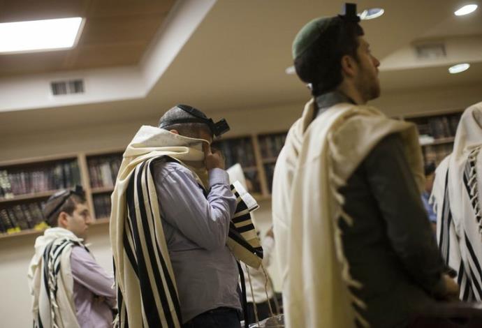 תפילת שחרית במקום הפיגוע בבית הכנסת בירושלים (צילום:  רויטרס)