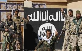 לוחמי מליציה שיעית ליד דגל דאעש בתיכרית (צילום: רויטרס)