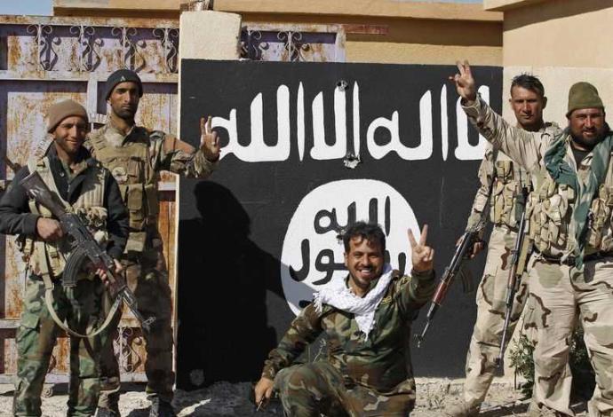 לוחמי מליציה שיעית ליד דגל דאעש בתיכרית (צילום:  רויטרס)