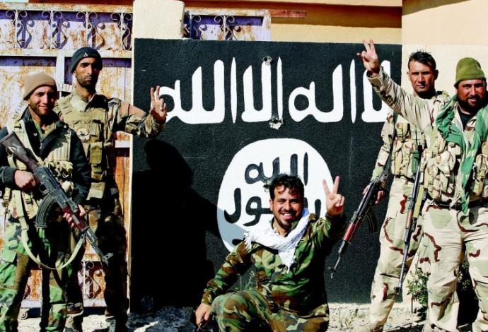 אנשי המליציה השיעית ליד דגל דאעש (צילום:  רויטרס)