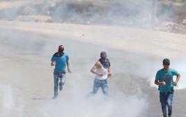 פלסטינים בורחים אחרי שצה"ל ירה גז מדמיע לעברם (צילום: רויטרס)
