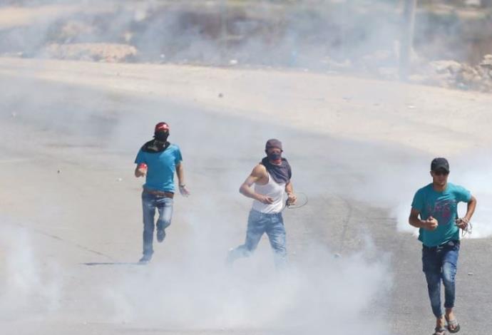 פלסטינים בורחים אחרי שצה"ל ירה גז מדמיע לעברם (צילום:  רויטרס)