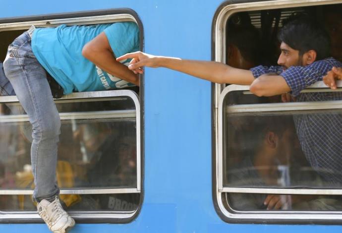 גם דרך החלון. מהגרים עולים לרכבת בקרואטיה (צילום:  רויטרס)