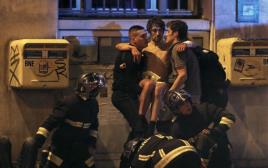כבאים מחלצים פצועים מאולם בטקלן בפריז  (צילום: רויטרס)