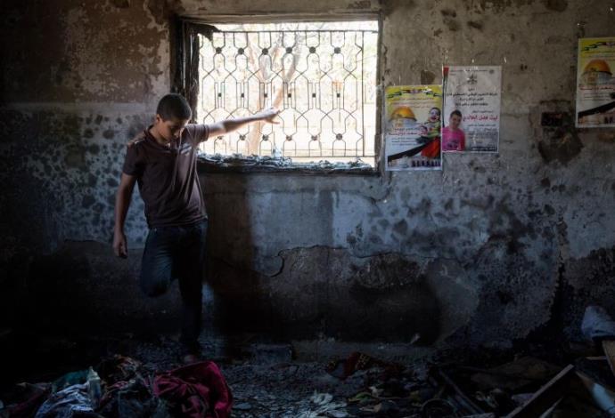 נער פלסטיני מביט על הנזק בבית שהוצת בדומא  (צילום:  מרים אלסטר, פלאש 90)