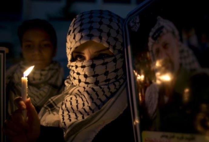 אשה פלסטינית מחזיקה נר בזמן הפגנה בדרום רצועת עזה (חאן יונס) (צילום:  AFP)