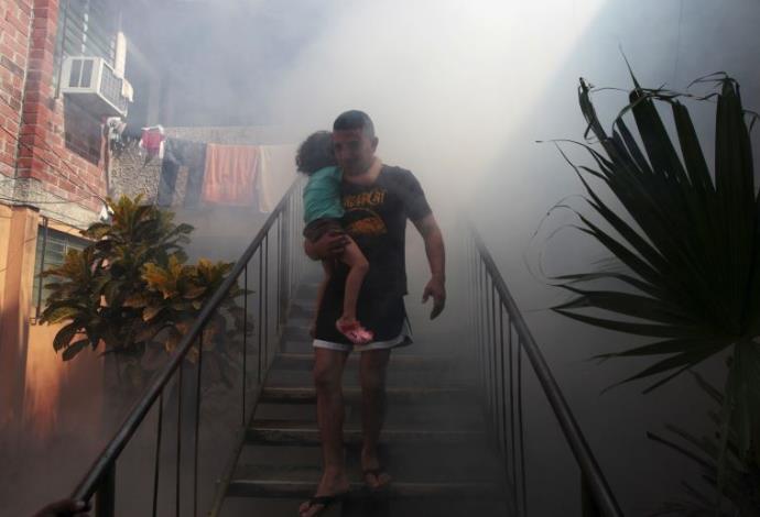 אדם מאל סלבדור ובנו יוצא מביתו לאחר שרשויות הבריאות ריססו אותו נגד הנגיף (צילום:  רויטרס)