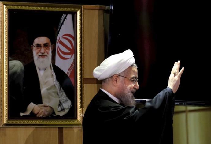 נשיא איראן רוחאני עם תמונתו של האייטולה חמינאי ברקע (צילום:  רויטרס)