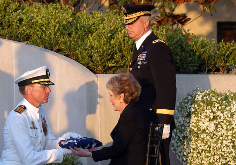 סרן ג'יימס א. סיימונדס מעניק את הדגל שכיסה את ארון בעלה לננסי רייגן בהלווייתו. צילום: ויקיפדיה