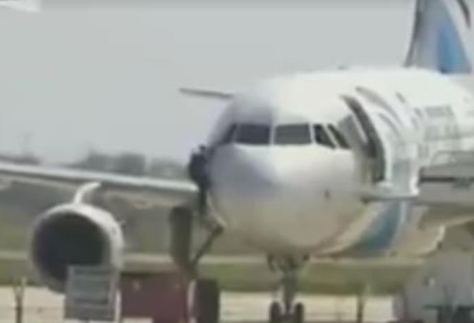 חוטף המטוס המצרי יוצא דרך חלון תא הטייס (צילום:  צילום מסך פייסבוק)
