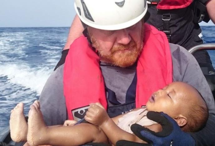 עובד הסיוע וגופת התינוק, ביום שישי מול חופי לוב (צילום:  רויטרס)