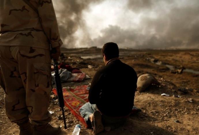 לוחם עיראקי עם שבוי מהמדינה האסלאמית (צילום:  רויטרס)